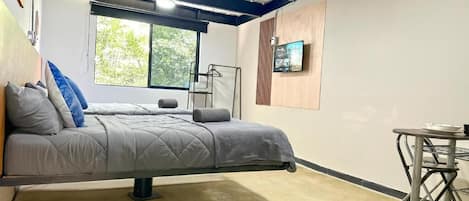 Een kamer met een bed, een bureau, een stoel, een televisie en een raam.
