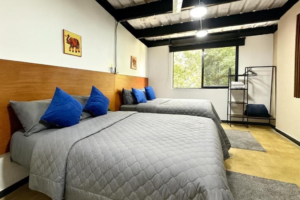 A room with two beds, a window, and a metal rack.
