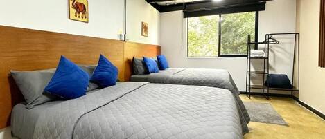 A room with two beds, a window, and a metal rack.