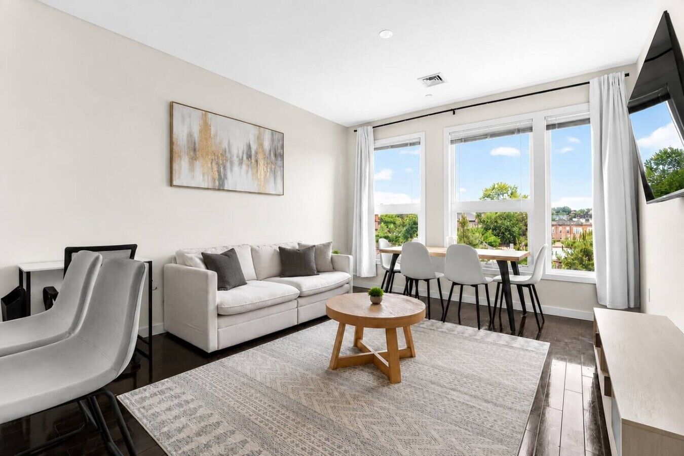 A modern living room with a sofa, chairs, a coffee table, and a painting on the wall.