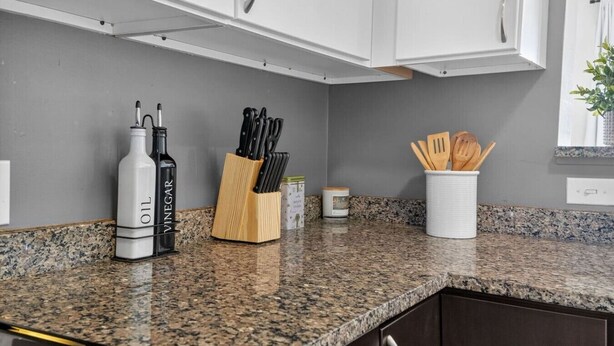 A kitchen with granite countertops, white cabinets, and a variety of kitchen utensils. - NEW! LUX 1BR w/ 400 Mbps Wifi | ROKU TV & Games! (Chelsea)