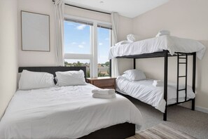 Ein Hotelzimmer mit Etagenbett, einem Einzelbett und einem großen Fenster mit Aussicht.