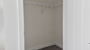 A closet with a white interior, a hanging rod, and a carpeted floor. - NEW! LUX 1BR w/ 400 Mbps Wifi | ROKU TV & Games! (Chelsea)