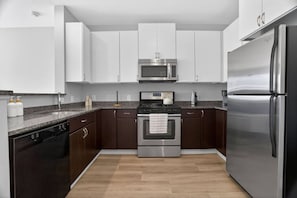 Una cocina moderna con electrodomésticos de acero inoxidable, armarios oscuros y una encimera de granito.