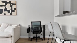 Un salon moderne avec un canapé blanc, un fauteuil de bureau noir et un fauteuil gris.