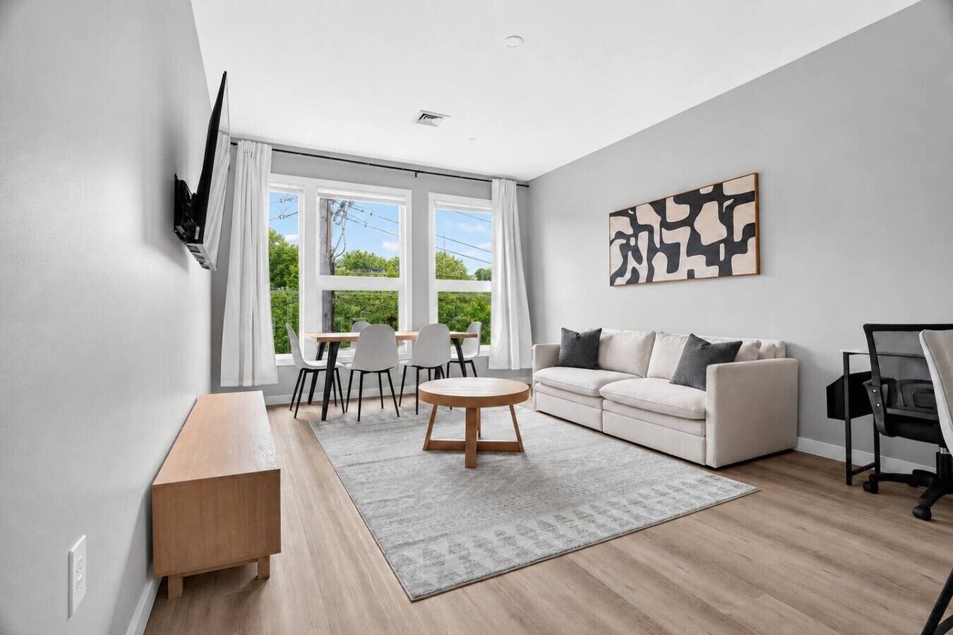 A modern living room with a sofa, a coffee table, and a TV mounted on the wall.