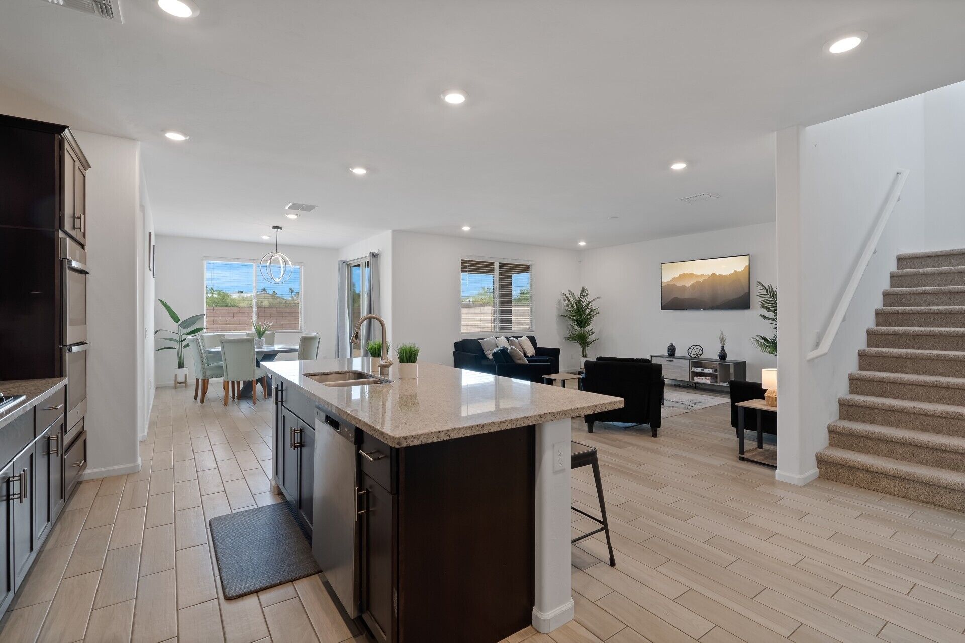A spacious living area with a kitchen, dining area, and a staircase leading to an upper level.