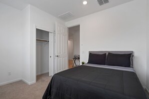 Ein Schlafzimmer mit einem Bett, einem Kleiderschrank und einem kleinen Tisch mit einer Pflanze.