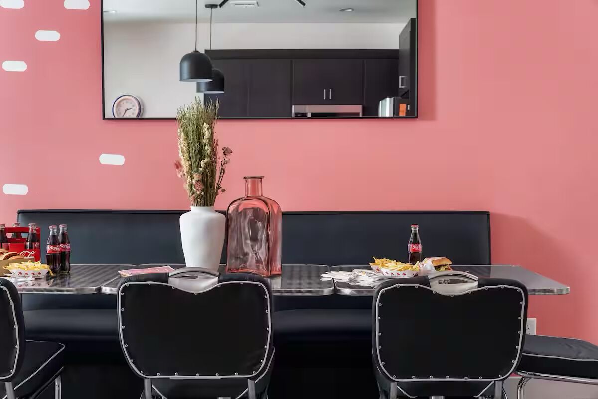 Un comedor moderno con una mesa negra, sillas y un florero.