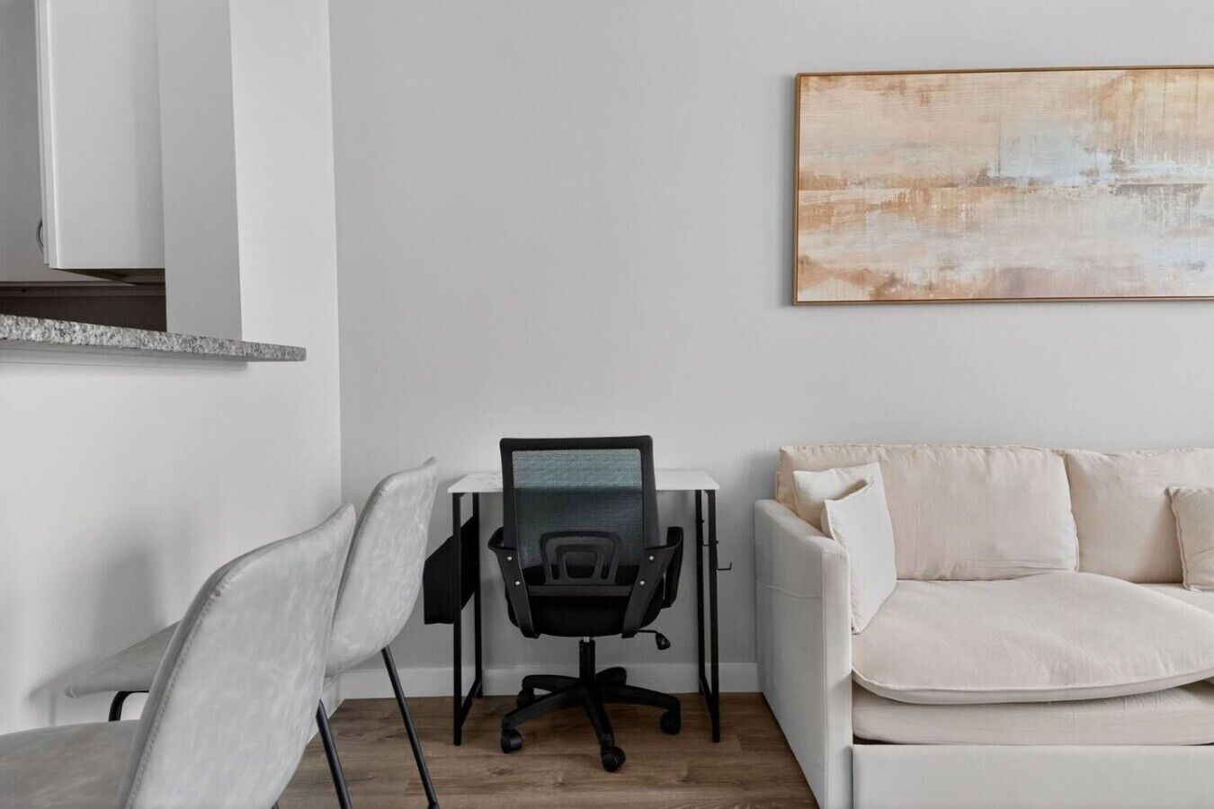 A modern office space with a desk, chair, and a white sofa.
