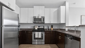 Une cuisine moderne dotée d’appareils électroménagers en acier inoxydable, de meubles de cuisine en bois foncé et d’un plan de travail en granit.