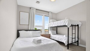 Une chambre d’hôtel avec un lit superposé, un lit simple et une grande fenêtre avec des rideaux.