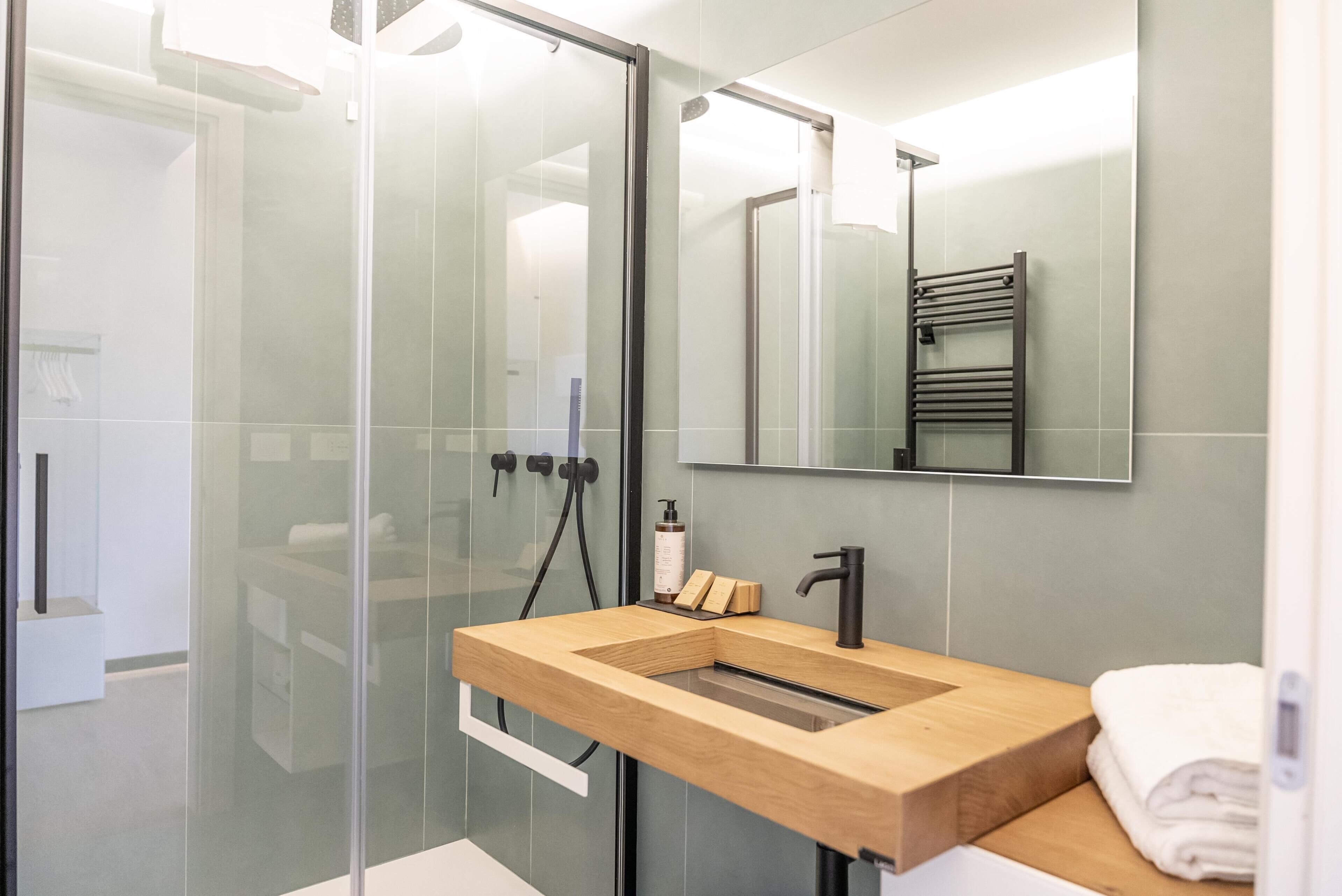 A modern bathroom with a glass shower enclosure, a wooden vanity, and a large mirror.