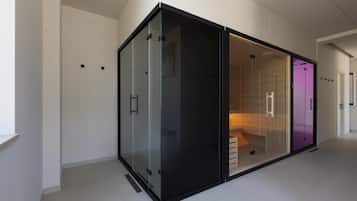 Un interior moderno con un amplio ventanal corredera de marco negro que da a una habitación con una cama y un armario iluminado en morado.