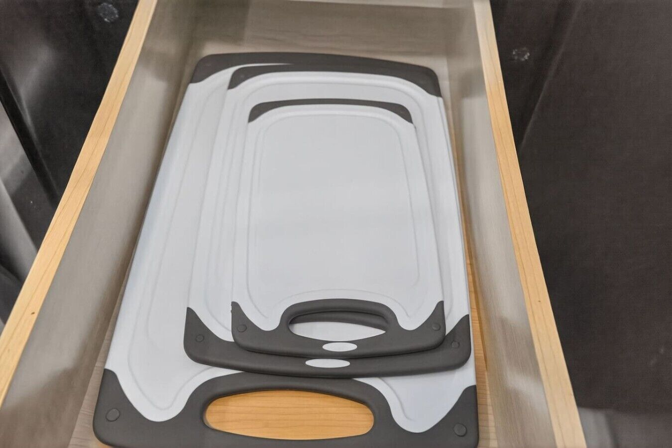 Uma gaveta com um objeto branco e preto lá dentro, possivelmente uma ferramenta de limpeza ou eletrodoméstico.