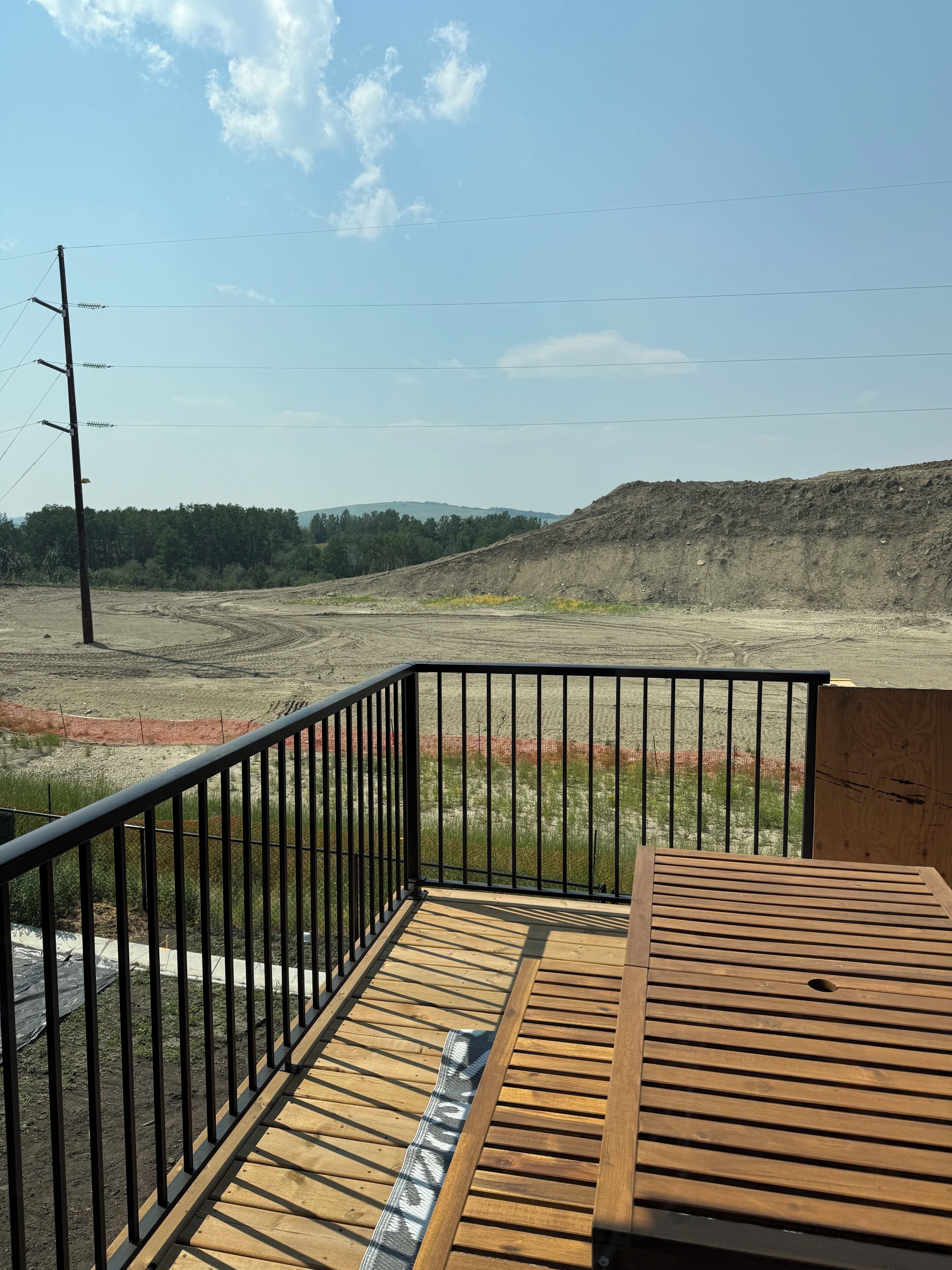 A wooden deck with a metal railing overlooking a construction site.