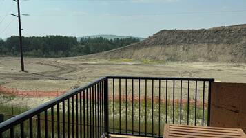 A wooden deck with a metal railing overlooking a construction site.