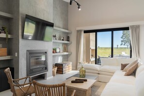 Una sala de estar moderna con chimenea, un sofá, una mesa de centro y vistas al exterior.