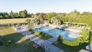 A swimming pool with a wooden deck, lounge chairs, and a gazebo.