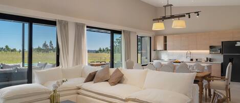 A modern living room with a large sofa, dining area, and kitchen.