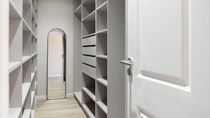 Um corredor estreito com armários embutidos nas paredes laterais, levando a uma porta com olho de fechadura.
