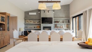 Uma cozinha moderna com área de refeições, apresentando bancada de mármore, iluminação pendente e lareira.