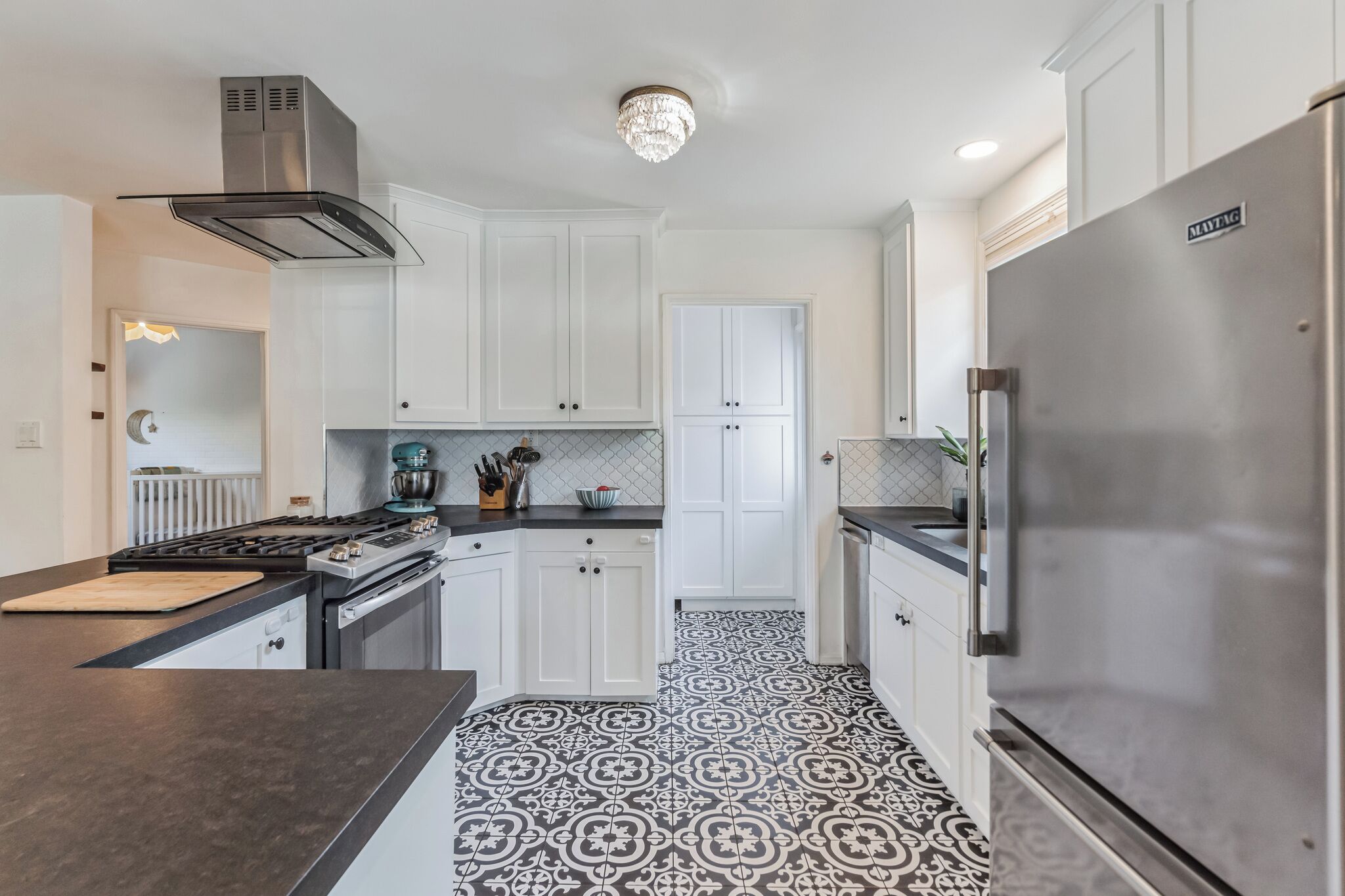 A modern kitchen with white cabinetry, a stainless steel refrigerator, and a patterned floor.