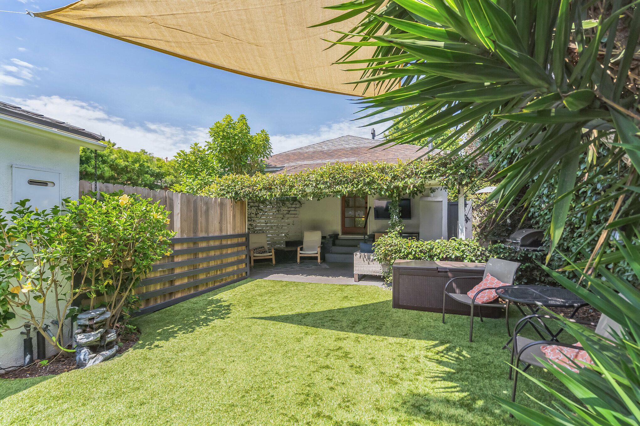 A backyard with a patio, seating area, and a covered section.