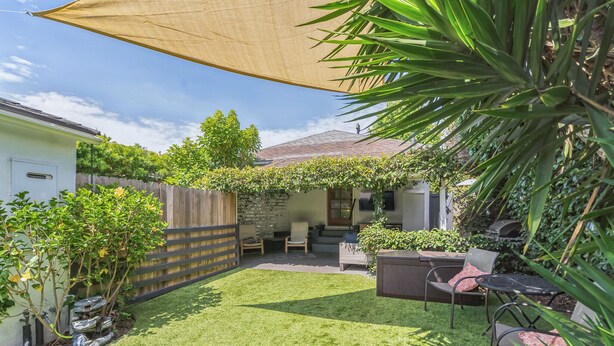 Un jardin avec une terrasse, un espace salon et une partie abritée.