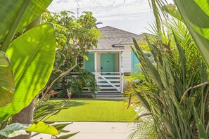 A small house with a green door, surrounded by lush greenery and a well-maintained lawn. - West LA Beachy Bungalow (Los Angeles)