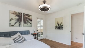 Une chambre à coucher avec un lit, un ventilateur de plafond et des œuvres d’art accrochées aux murs.