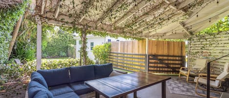 An outdoor patio with a blue sofa, a wooden table, and a wooden fence.