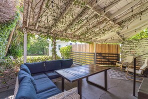 Une terrasse extérieure avec un canapé bleu, une table en bois et une clôture en bois.