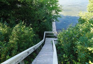 A wooden staircase leading down to a body of water, surrounded by dense greenery. - Historic Lakefront Farmhouse on Battle Lake - Sleeps 9 (Battle Lake)