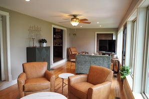 A modern living room with leather armchairs, a grey sofa, a dining table, and a ceiling fan. - Historic Lakefront Farmhouse on Battle Lake - Sleeps 9 (Battle Lake)