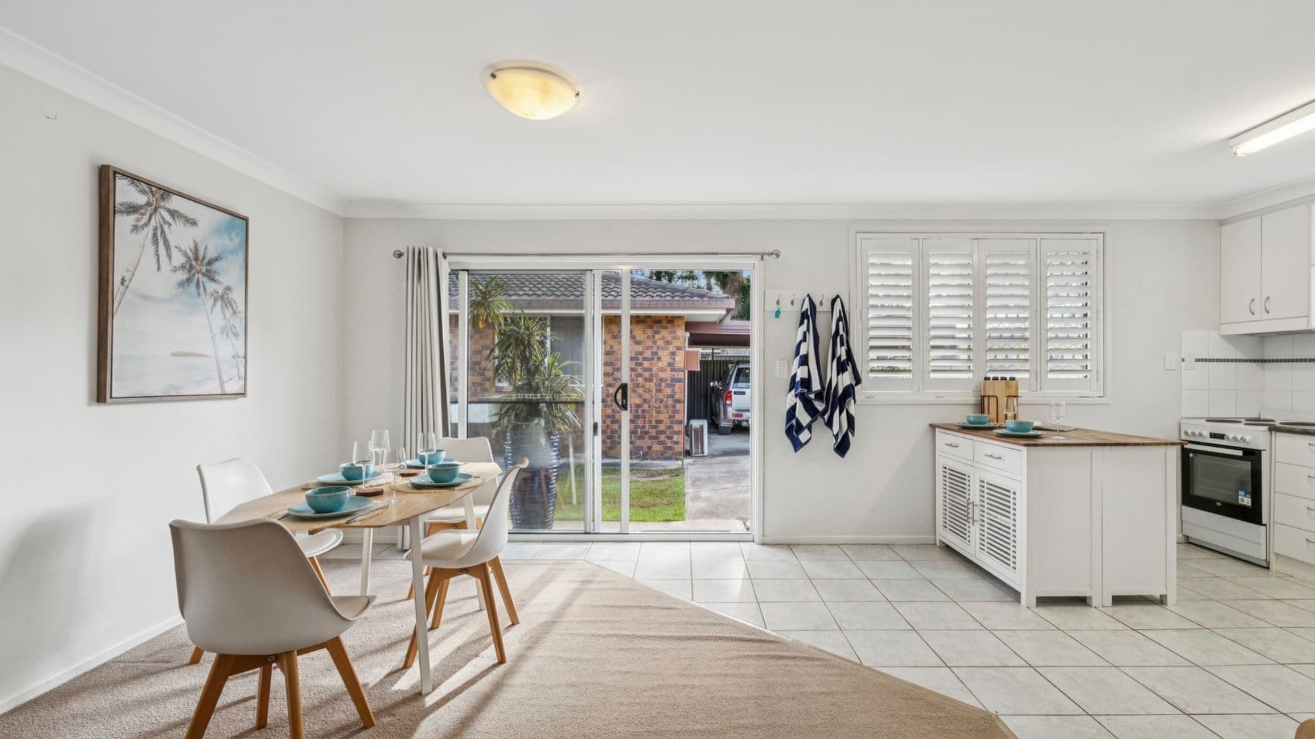 A modern kitchen with white cabinets, a built-in oven, and a dining area with a table set for four.