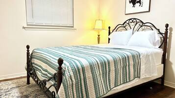 A bed with a striped quilt, a bedside lamp, and a wall-mounted picture.