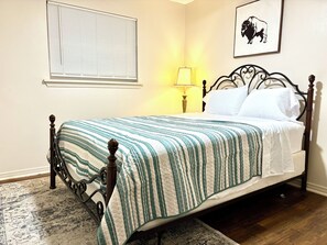 Uma cama com um edredom listrado, um abajur e um quadro pendurado na parede.
