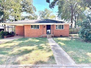 A single-story brick house with a front porch, a covered patio, and a well-maintained lawn. - Bison Hall 11, Cozy 3 bedroom/2 bath home, close to Harding, no cleaning fee. (Searcy)