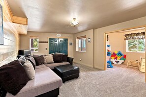 A room with a sectional sofa, a door with a 'Happy' sign, and a window with blinds. - 5-Bedroom Family Cabin with 3 King Beds & Mountain Views in Duck Creek Village (Duck Creek Village)