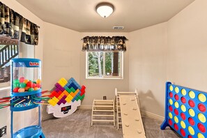 A child's playroom with a window, a claw machine, a Tetris game, and a pop-it toy. - 5-Bedroom Family Cabin with 3 King Beds & Mountain Views in Duck Creek Village (Duck Creek Village)