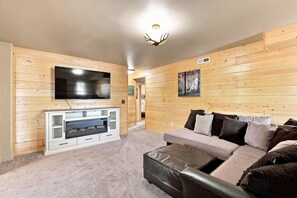 Ein Wohnzimmer mit Flachbildfernseher, Kamin, Sofa und einer Holzwand.