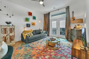 A living room with a sofa, a coffee table, a cabinet, and a guitar. - Adorable Downtown Getaway (Asheville)