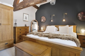 Un dormitorio con una cama de madera, un tocador, un espejo e iluminación en la pared.