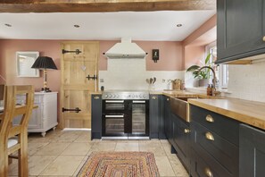 Una cocina con armarios de madera, horno empotrado y una ventana con una planta.