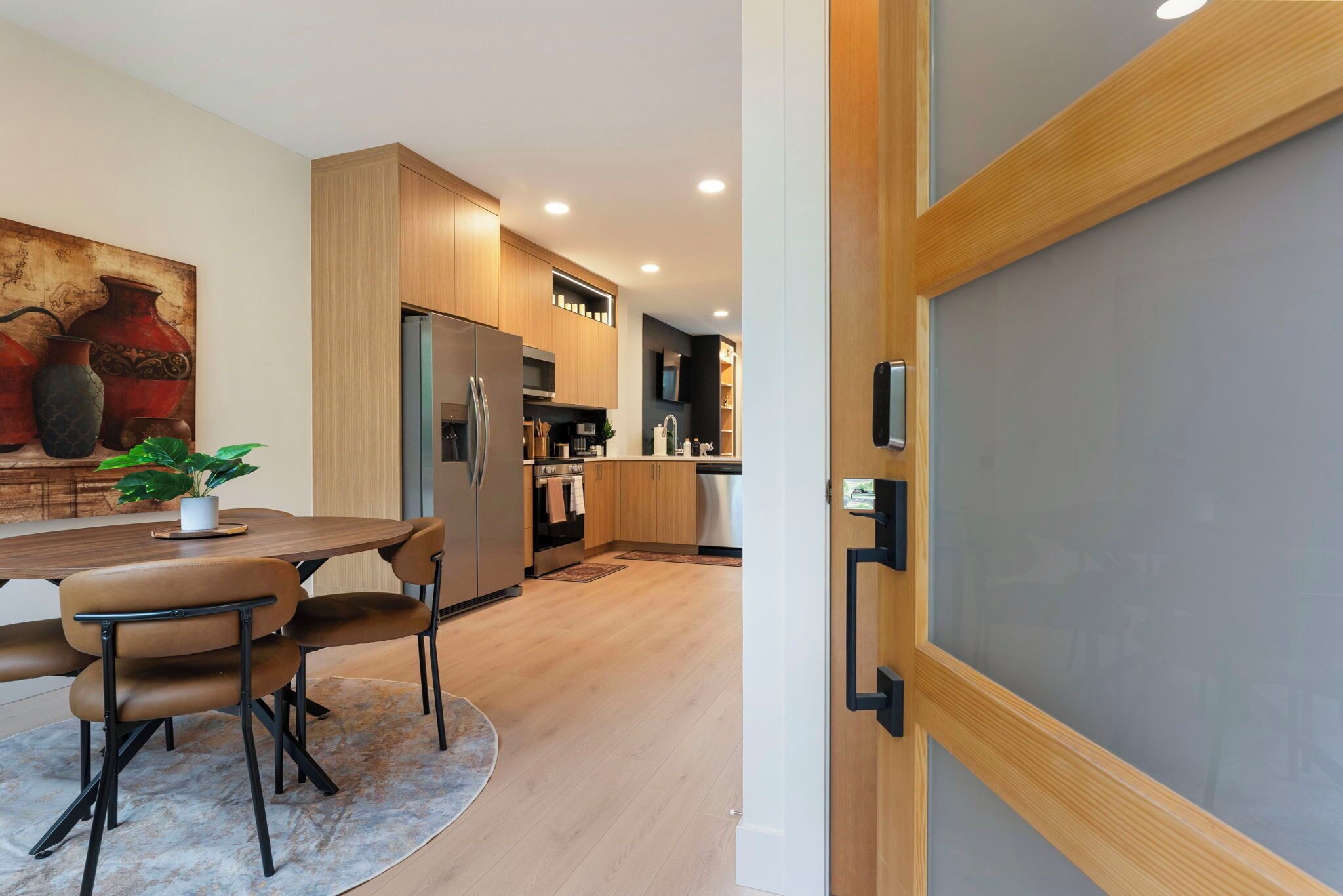 A modern kitchen with wooden cabinets, stainless steel appliances, and a dining area with a table and chairs.