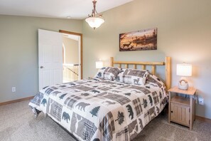 A bedroom with a bed, a nightstand, a lamp, a painting, and a door. - Charming 3-bedroom, 3 bathroom house in a peaceful, cozy place with AC. (Parkers Prairie)