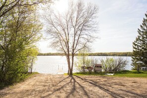 A dirt path leading to a dock by a lake with trees on both sides. - Charming 3-bedroom, 3 bathroom house in a peaceful, cozy place with AC. (Parkers Prairie)