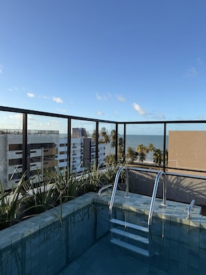 A rooftop pool with a view of the ocean and palm trees. - Flat Cabo Branco 50m do mar 205  (João Pessoa)