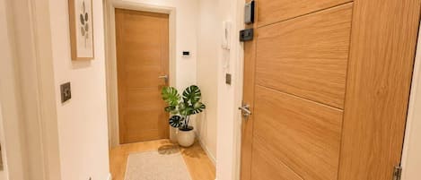 A hallway with wooden doors, a potted plant, and a light switch on the wall.